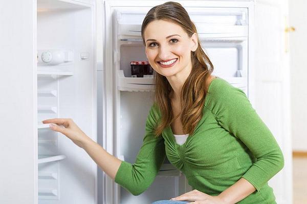 Девушка стоит около открытого холодильника